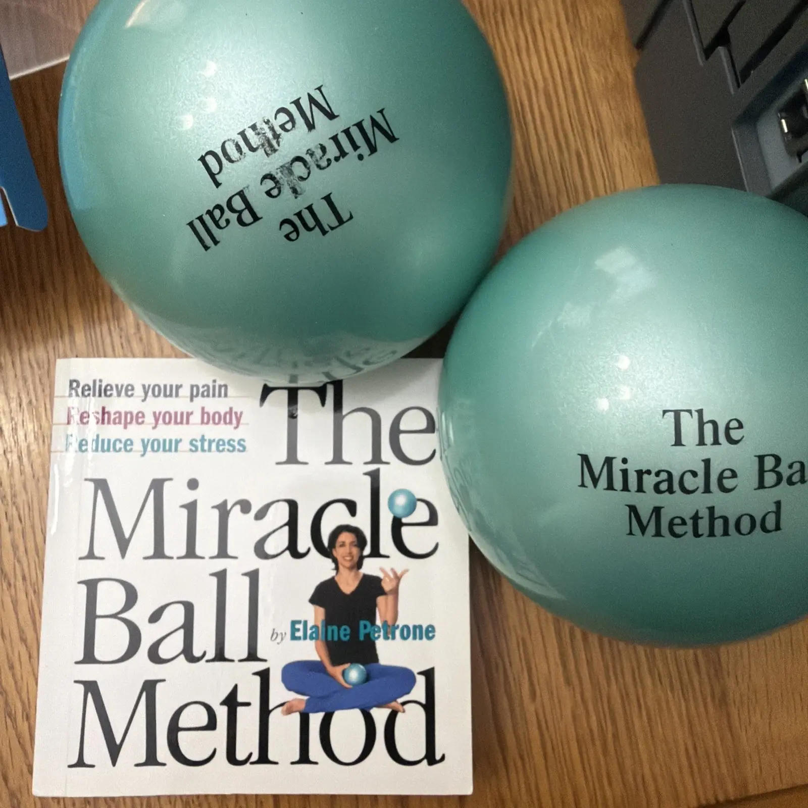 Two teal Miracle Balls beside The Miracle Ball Method book by Elaine Petrone
